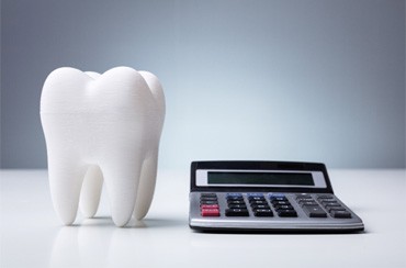 Tooth next to a calculator on a white desk 