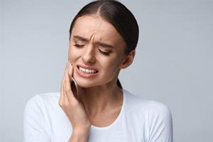 woman in white shirt with severe dental pain