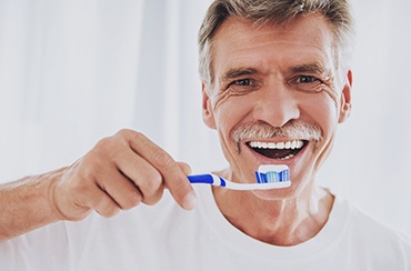man brushing his teeth and maintaining good oral hygiene