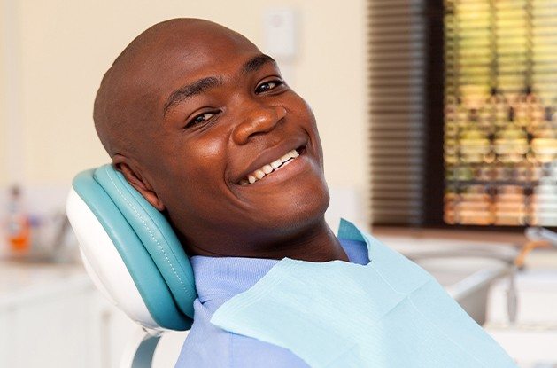man smiling at camera laying back in exam chair
