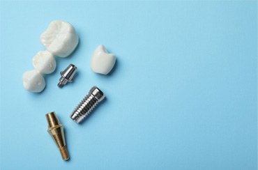 The parts of a dental implant and bridge on a light blue background