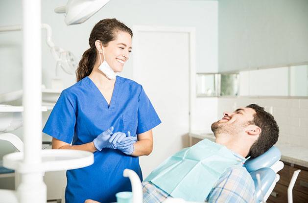 Dentist and patient smiling at each other in office