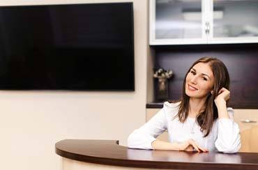 Dental employee smiling while sitting at a desk