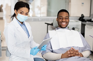 patient and dentist smiling while looking at camera 