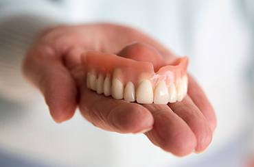 Close-up of a hand holding dentures in East Longmeadow, MA