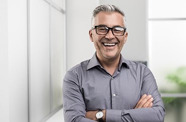 Man with glasses smiling with his arms folded