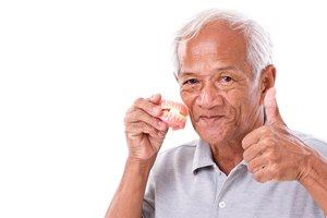 man holding denture doing thumbs up