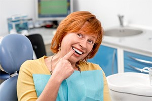 woman in yellow shirt pointing to smile