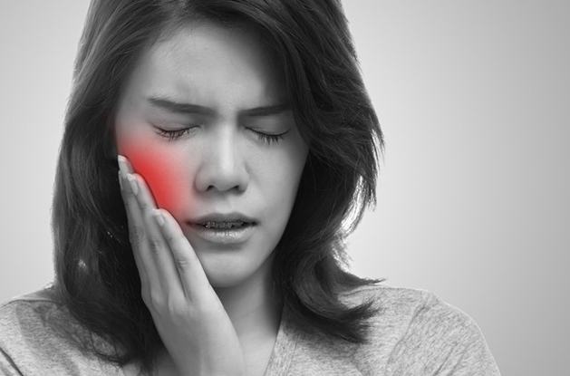 woman holding cheek in pain