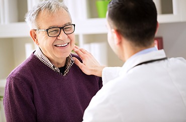 Smiling patient and dentist talking about the cost of dental implants