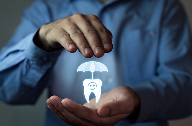 hand holding tooth with umbrella