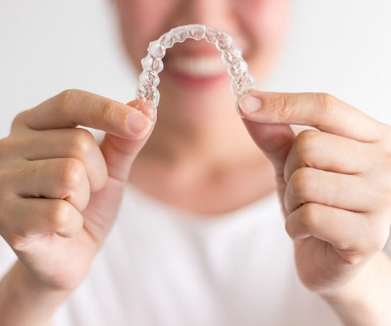 Closeup of patient holding up Invisalign in East Longmeadow