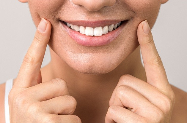 woman using both hands to point to smile