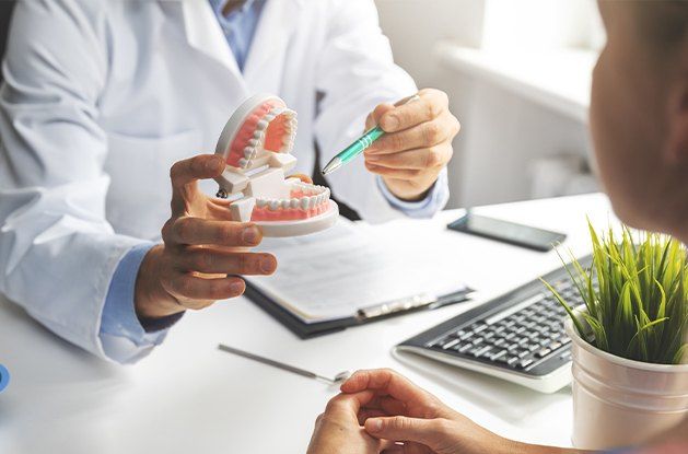 dentist pointing to mock teeth