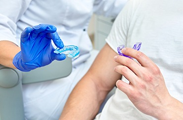 A dentist and patient holding two distinct mouthguards