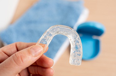 A woman holding a mouthguard over a blurred storage case