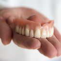 Hand holding a full denture