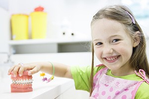 young girl holding teeth with braces