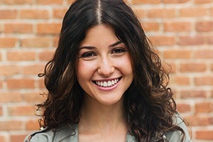 girl smiling against brick wall