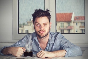 man very tired holding coffee cup