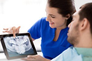 woman in blue scrubs pointing to x-ray