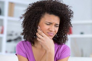 woman in purple shirt wincing in pain