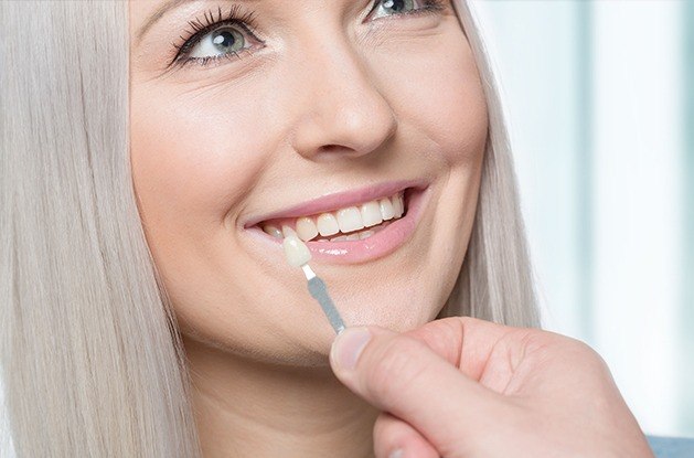 woman having veneer checked against teeth