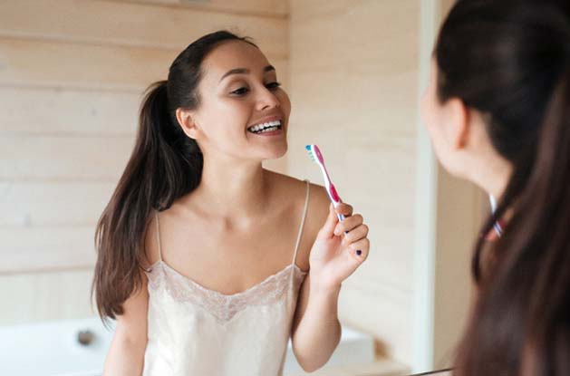 Woman brushing teeth after teeth whitening in Northampton