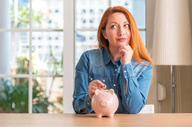 Woman putting coin in piggy bank for teeth whitening in Northampton