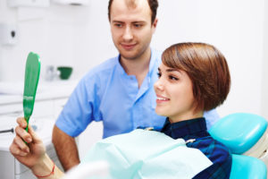 Dentist and patient looking at smile in mirror