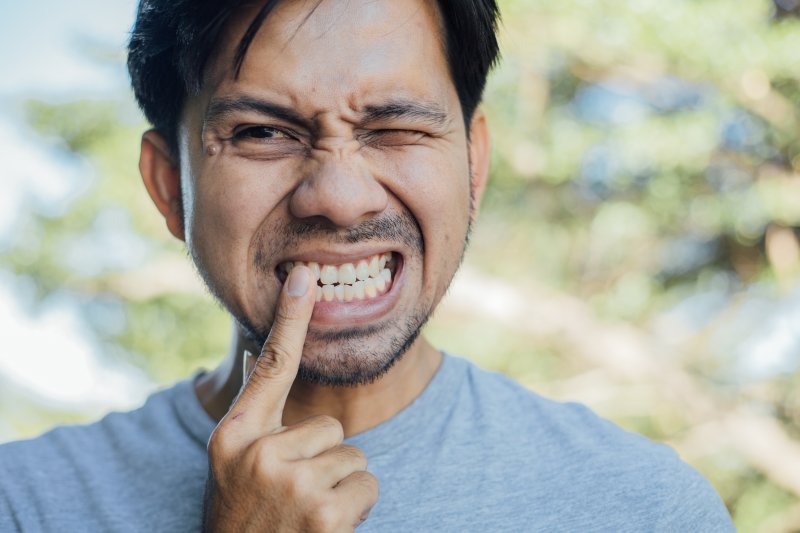 man touching loose dental implant in East Longmeadow & Northampton