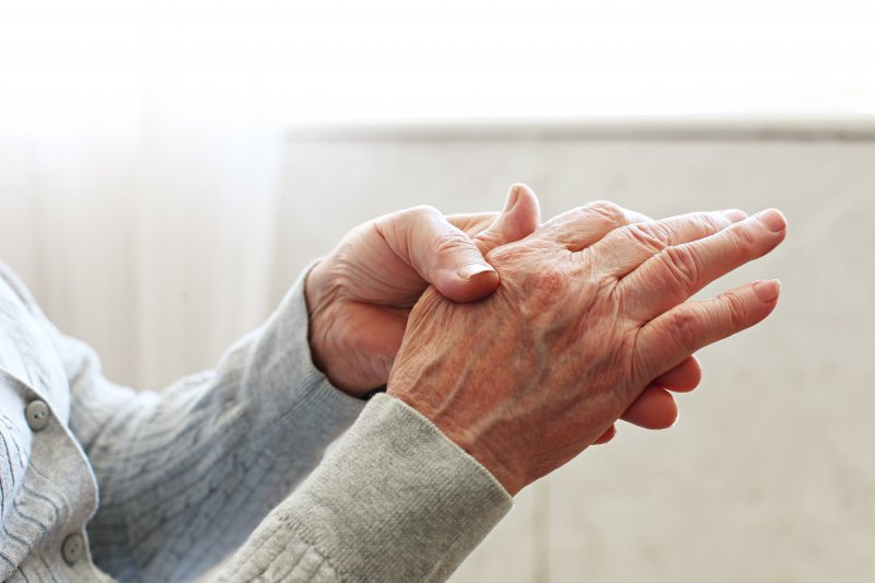 Elderly person holding their hand in pain.