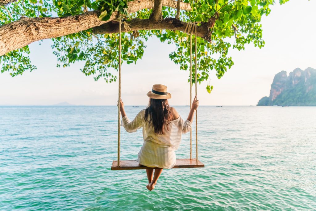 Woman swinging on swing over the ocean