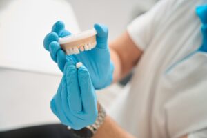 a dentist holding a dental crown and mouth mold